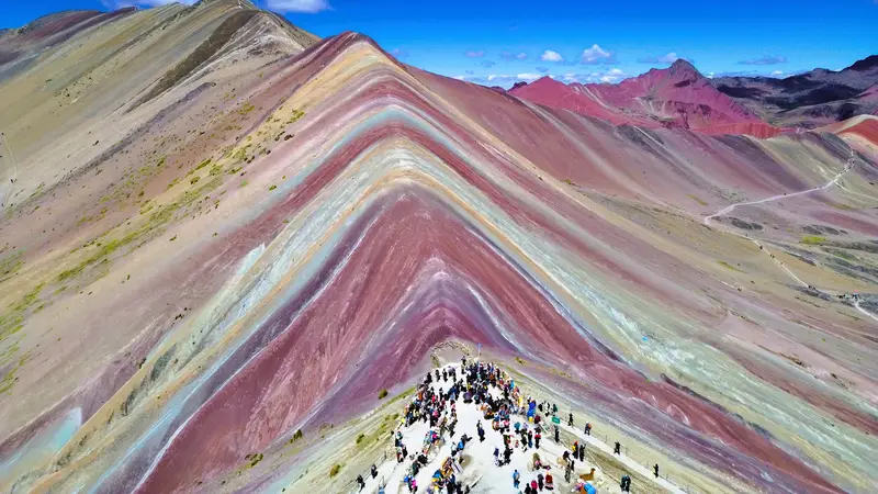 Grupo de viajeros disfrutando de la increible vista panoramica de los minerales de la montana Vinicunca.