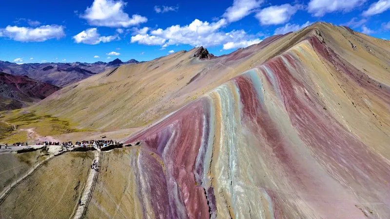 Turistas reunidos en el mirador principal apreciando las increibles formaciones geologicas de la montana Vinicunca.