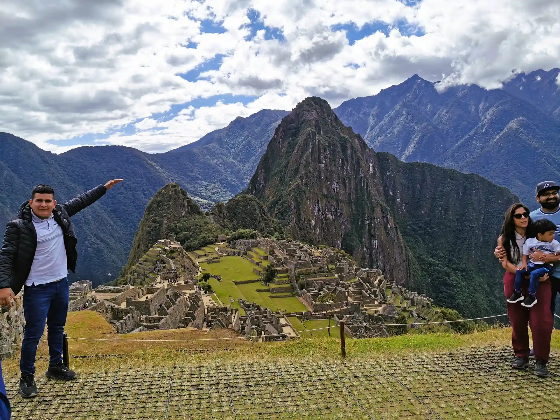 Turistas disfrutando de la vista clásica de Machu Picchu y sus terrazas agrícolas en un día despejado.