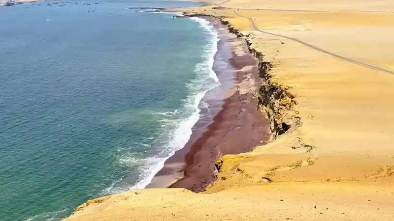 Toma aerea de los acantilados del desierto y la costa de Playa Roja en la Reserva Nacional de Paracas Peru.